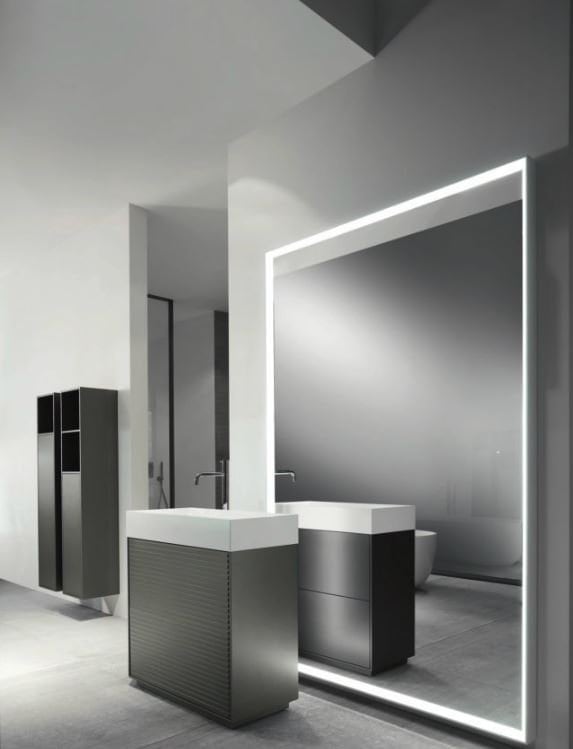 Specchio illuminato e arredi minimalisti in un bagno elegante e contemporaneo.